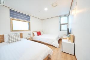 two beds in a room with two windows at K'STAY Sinchon in Seoul