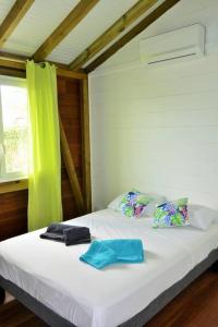una camera con un letto bianco con una tenda verde di Bungalow Belvu 2chb - piscine personnelle a Le Marin