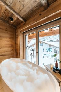 a bath tub in a room with a window at Hotel Maiensee in Sankt Christoph am Arlberg