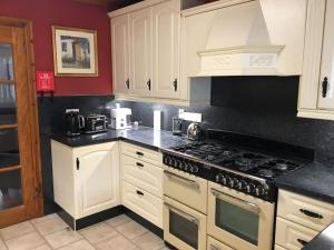 a kitchen with white cabinets and a stove top oven at Comfy Cottage in Ballymena
