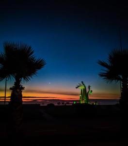 una vista de la puesta de sol desde la playa con 2 palmeras en Hostal LG Laraquete en Laraquete