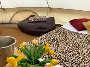 um quarto com uma cama e flores sobre uma mesa em Home Farm Radnage Glamping Bell Tent 6, with Log Burner and Fire Pit em High Wycombe