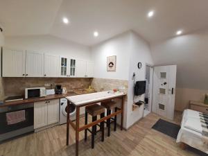 a kitchen with white cabinets and a table and chairs at Luna Apartman in Eger