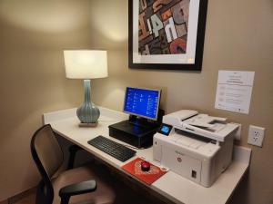 einen Schreibtisch mit einem Drucker und einem Computer darauf in der Unterkunft Candlewood Suites Greenville NC, an IHG Hotel in Greenville