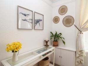 a white table with a vase of flowers and pictures on the wall at Oystercatcher Bay in Weymouth