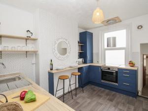 a kitchen with blue cabinets and a table with stools at Oystercatcher Bay in Weymouth