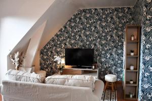 a living room with a white couch and a tv at Cœur des chevaux in Deauville