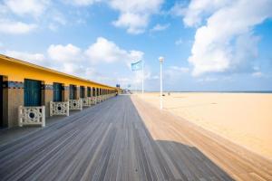 a boardwalk on a beach with a building and a flag at Cœur des chevaux in Deauville