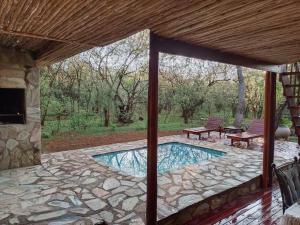 an outdoor patio with a swimming pool and two chairs at Hoedspruit Bush Cottage in Hoedspruit