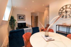 sala de estar con mesa, sillas y reloj en Furness House by Pay As U Stay en Redhill