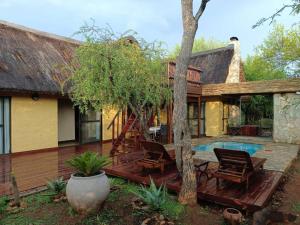 a house with a wooden deck and a swimming pool at Hoedspruit Bush Cottage in Hoedspruit