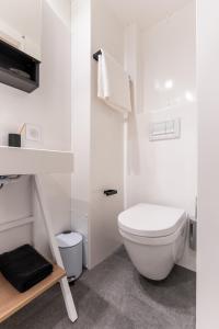 La salle de bains blanche est pourvue de toilettes et d'un tabouret. dans l'établissement Ecla Paris Villejuif, à Villejuif