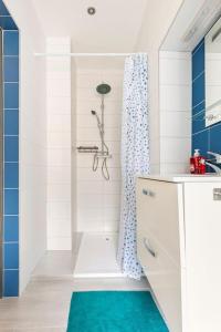 a white bathroom with a shower with a blue shower curtain at Le studio in Lembach