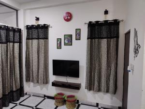 ein Wohnzimmer mit 2 Vorhängen und einem TV in der Unterkunft AK Corbett Family Homestay in Rāmnagar