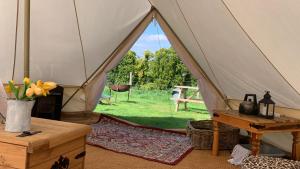 a canvas tent with a view of a yard at Home Farm Radnage Glamping Bell Tent 6, with Log Burner and Fire Pit in High Wycombe