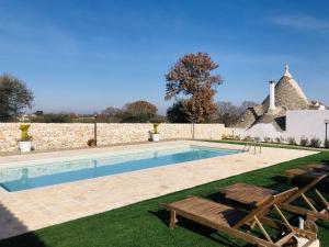 a swimming pool with two chairs and a house at i Trulli del Fauno in Alberobello