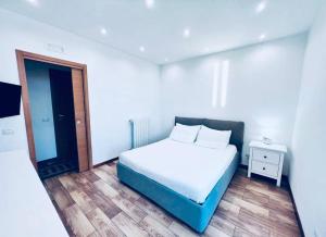a white bedroom with a bed and a night stand at Macario Apartment in the Old Town in Bari