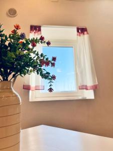 un vaso con fiori seduto su un tavolo accanto a una finestra di Macario Apartment in the Old Town a Bari