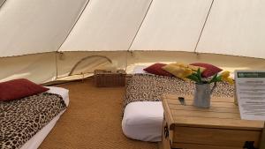ハイ・ウィカムにあるHome Farm Radnage Glamping Bell Tent 7, with Log Burner and Fire Pitのベッド2台、テーブルに花瓶を用意しています。