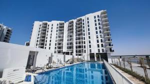 a hotel with a swimming pool in front of a building at Modern Apartment in Racing Paradise: Close to Ferrari World & F1 Track in Abu Dhabi