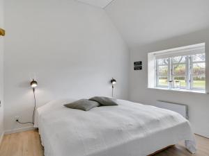 een witte slaapkamer met een bed en een raam bij Holiday Home Filippus - 30km from the sea in Western Jutland by Interhome in Tønder