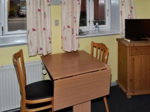 a wooden desk with two chairs and a computer at Apartment Gunhild - 22km from the sea in Western Jutland by Interhome in Bredebro