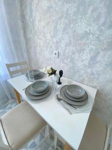 a white table with plates and flowers on it at INJU апартаменты in Taldykolʼ