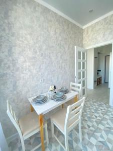 a dining room with a white table and chairs at INJU апартаменты in Taldykolʼ