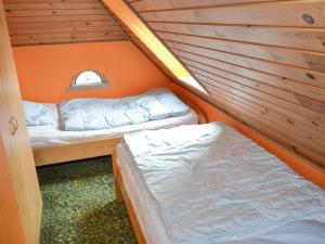 Duas camas num pequeno quarto com uma parede laranja em Holiday Home Marinka - 8km from the sea in Western Jutland by Interhome em Højer