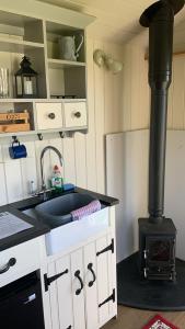 a kitchen with a stove and a counter with a sink at Home Farm Shepherds Hut with Firepit and Wood Burning Stove in High Wycombe