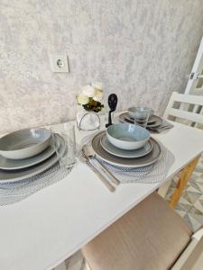 a white table with plates and utensils on it at INJU апартаменты in Taldykolʼ