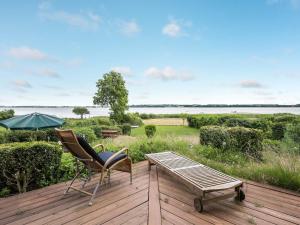 a deck with a chair and a table and an umbrella at Holiday Home Brunman - 10m to the inlet in Sealand by Interhome in Grevinge