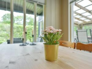 un jarrón amarillo con flores rosas sentado en una mesa en Holiday Home Saima - 25km from the sea in Western Jutland by Interhome en Toftlund