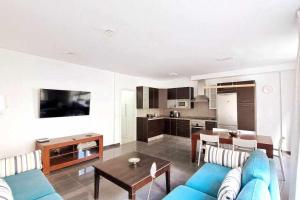 a living room with a blue couch and a kitchen at ARQ Home Arrecife in Arrecife