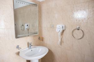 een badkamer met een wastafel, een spiegel en een telefoon bij VILA SANREMO in Tirana