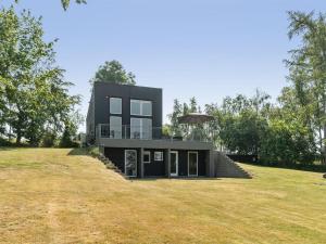 a black house on top of a grass field at Holiday Home Harka - 100m to the inlet in Sealand by Interhome in Roskilde