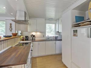 a kitchen with white cabinets and a white refrigerator at Holiday Home Pinja - 40km from the sea in SE Jutland by Interhome in Silkeborg