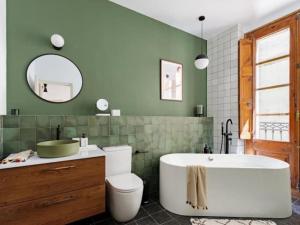 a bathroom with a tub and a green wall at Spacious apartment in the Gothic in Barcelona