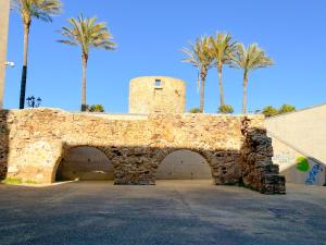 a stone wall with a gate and palm trees at POMA DE CASA - Carrer de Pa i Algua in Alghero