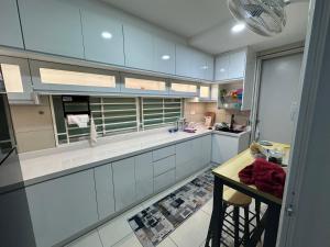 a large kitchen with white cabinets and a table at Suraya Homestay V’ Residence in Puchong