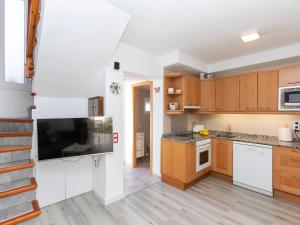 a kitchen with wooden cabinets and a flat screen tv at Villa Villa Casalot 9 by Interhome in Miami Platja