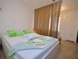 ein Bett mit grünen und weißen Kissen und Handtüchern darauf in der Unterkunft Apartment Borka-3 by Interhome in Trogir