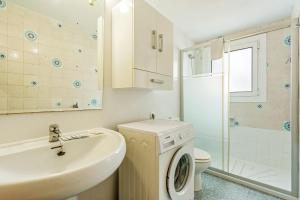 een badkamer met een wastafel en een wasmachine bij La Marina Apartments in Platja  d'Aro