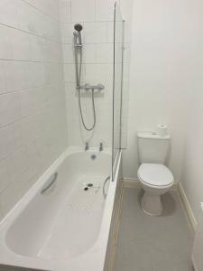 a white bathroom with a toilet and a bath tub at Cosy apartment near Newcastle in Gateshead