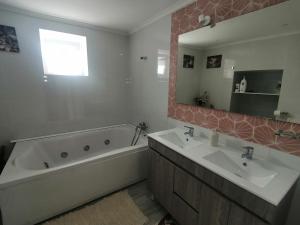 een badkamer met 2 wastafels, een bad en een spiegel bij Habitaciones Casa Santander Playa Valdenoja in Santander