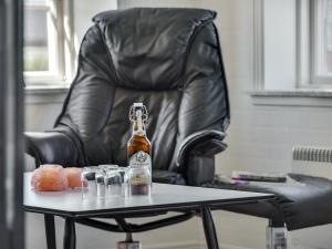 una botella de cerveza en una mesa frente a una silla de cuero en Holiday Home Ejna in Western Jutland by Interhome, en Bredebro