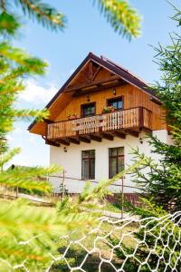 a wooden house with a balcony on top of it at Pensiunea Roua Apuseni Belis in Beliş