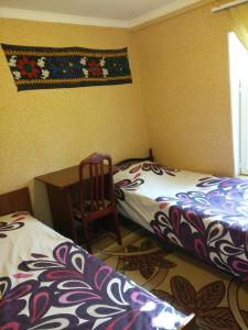 a bedroom with two beds and a desk and a chair at Sayfi Guesthouse in Dushanbe