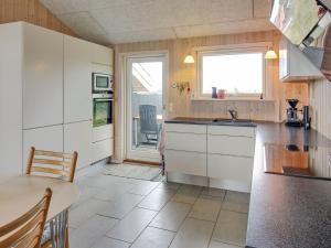 cocina con armarios blancos, mesa y ventana en Holiday Home Griselda - 700m from the sea in NW Jutland by Interhome en Torsted