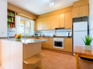 cocina con armarios de madera y nevera blanca en Apartment Majari by Interhome, en Vinarós